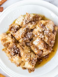 a white plate topped with food covered in powdered sugar next to some cinnamon sticks