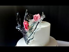 there is a white cake with pink flowers on the top and black icing around it