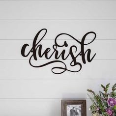 the word cherish is mounted on a wall above a table with flowers and a vase