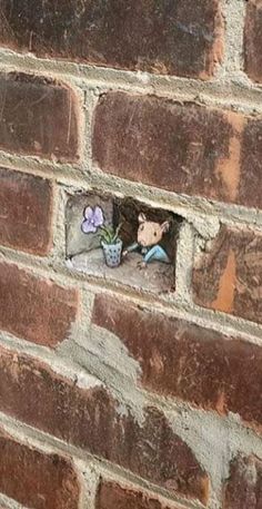 a brick wall with a hole in the middle that has stickers on it and flowers