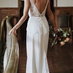 a woman in a wedding dress is walking down the stairs with her bouquet on her hand