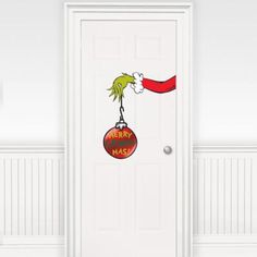 a door with a grin on it and a merry christmas ornament hanging from the front