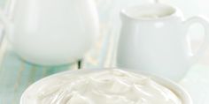 a bowl of whipped cream sitting on top of a table next to two white pitchers