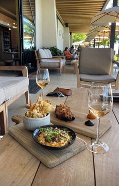 a wooden table topped with plates of food and glasses of wine on top of it