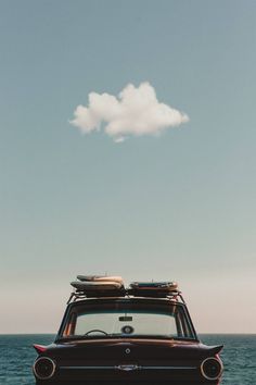 an old car parked on the beach with luggage strapped to it's roof rack