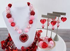 a necklace and earring set with red, white and pink hearts on display at a booth