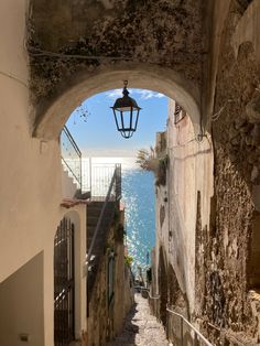 an alley way with stairs leading to the water and a light fixture hanging over it