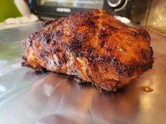 a piece of meat sitting on top of a metal table next to a microwave oven