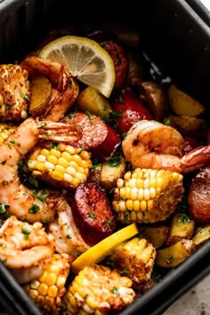 shrimp, corn on the cob and potatoes in a crock pot with lemon wedges