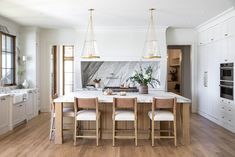 a large kitchen with marble counter tops and wooden flooring, along with white cabinets