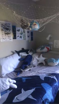 a bed that has some stuffed animals on it and is in a room with pictures hanging from the ceiling