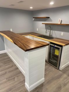 an empty kitchen with white cabinets and wood counter tops