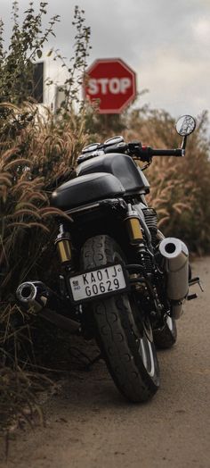 a motorcycle parked on the side of a road next to bushes and a stop sign