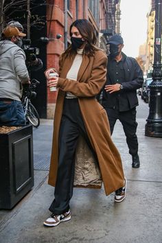 a woman wearing a face mask walking down the street with her hand in her pocket