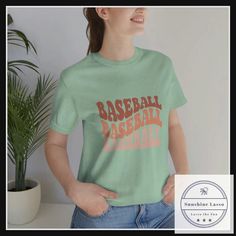 a woman wearing a green baseball t - shirt with the word baseball in red on it