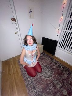 a woman sitting on the floor with a party hat on her head and red tights