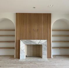 an empty room with wooden shelves and a fireplace