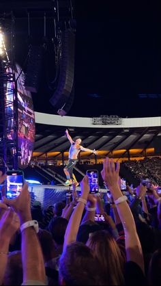 a man standing on top of a stage surrounded by people holding up their cell phones