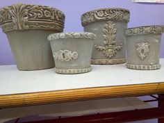 four ceramic pots sitting on top of a table