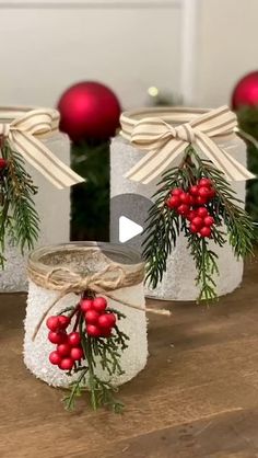 three mason jars decorated with holly and red berries are sitting on a wooden table in front of christmas decorations