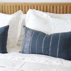 two blue and white pillows sitting on top of a bed next to a headboard