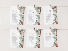 the table numbers are hanging from twine with holly leaves and berries on them, along with pine cones