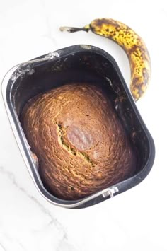 a banana sitting next to a loaf of bread in a pan on top of a counter