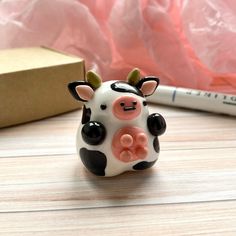 a small cow figurine sitting on top of a table next to a pen