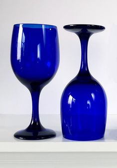 three blue glass vases sitting on top of a white shelf next to each other