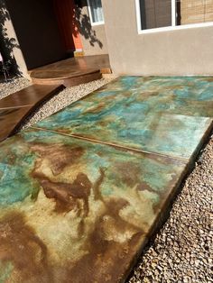 an outdoor area with rocks and gravel in front of a house that has been painted brown and blue