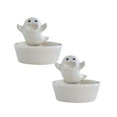 two small white bowls with ghost figurines sitting in them on a white background