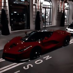 a red sports car parked in front of a building with people walking by on the sidewalk