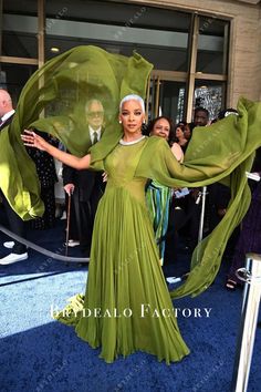 a woman in a green dress is posing on the blue carpet