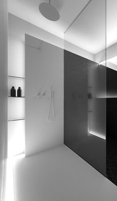 a black and white photo of a bathroom with shower, shelves and lights on the wall