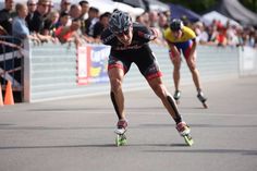 two men racing on roller skates in front of a large group of people watching