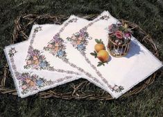 three placemats with fruit on them sitting in the grass next to a basket