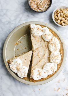 a pie sitting on top of a white plate next to other desserts and nuts