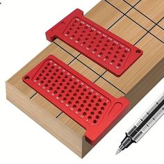 two red graters sitting on top of a wooden table next to a pen