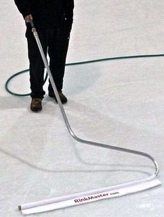 a man is using a hose to clean the ice with a snow blower on it