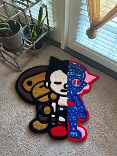 two rugs with cartoon characters on them in front of a window and a potted plant