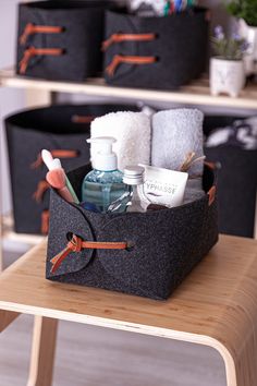 a black storage basket filled with toiletries on top of a wooden table