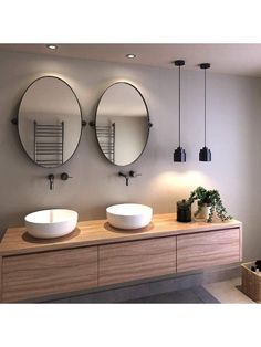 two round mirrors hanging on the side of a wall next to a wooden counter top