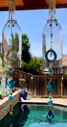 three wine glasses hanging from a wooden beam over a swimming pool in a back yard