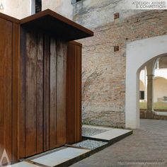 an open wooden door on the side of a building with brick walls and doorways