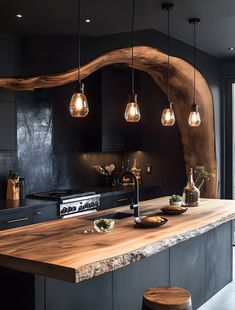 a kitchen with black cabinets and wooden counter tops, lights hanging from the ceiling over the island