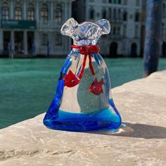 a glass vase sitting on top of a stone wall next to a body of water