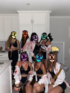 a group of women in costumes with glowing masks on their faces and holding axes, posing for the camera