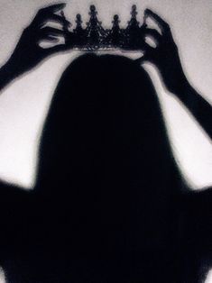 the shadow of a woman holding a crown over her head