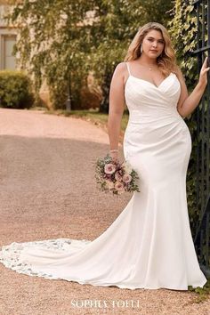 a woman in a wedding dress leaning against a gate