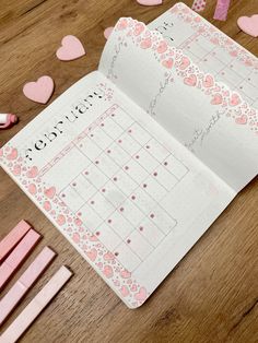 an open planner with hearts on it and pink erasers next to the pages that have been cut out